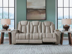Reclining sofa with three padded headrests and light beige fabric upholstery