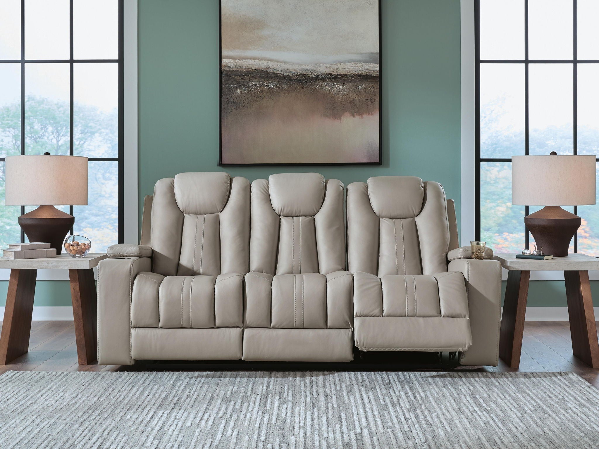 Reclining sofa with three padded headrests and light beige fabric upholstery