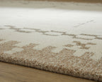 Flatweave area rug corner with light tan pile and beige abstract dot pattern