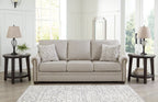 Light gray 3-seat sofa with two patterned throw pillows and rolled arms.