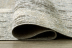 Rolled edge of washable area rug in beige and gray abstract texture, bound border