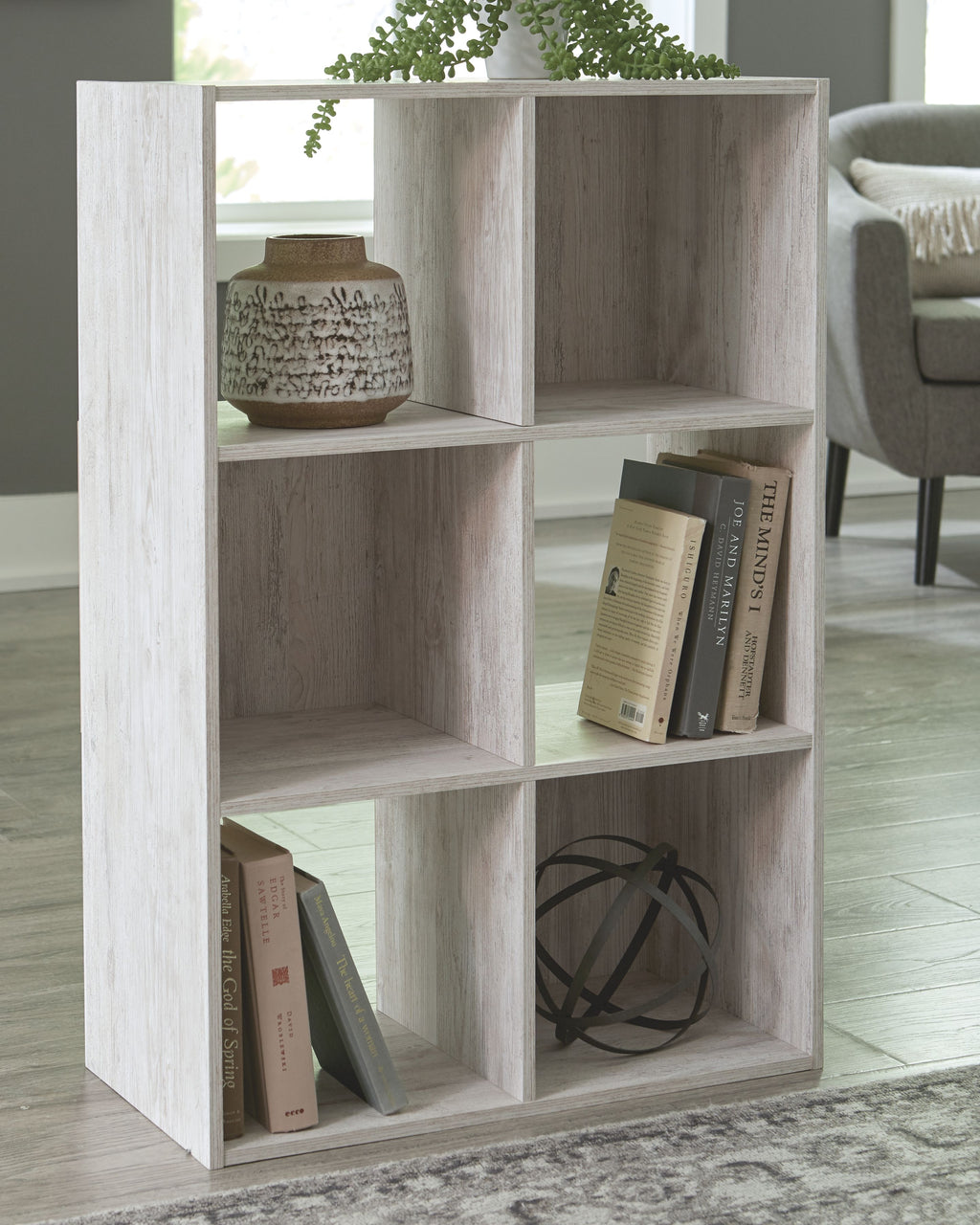 Whitewashed wood cube organizer with open cubbies holding books and decor