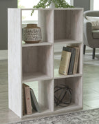 Whitewashed wood cube organizer with open cubbies holding books and decor