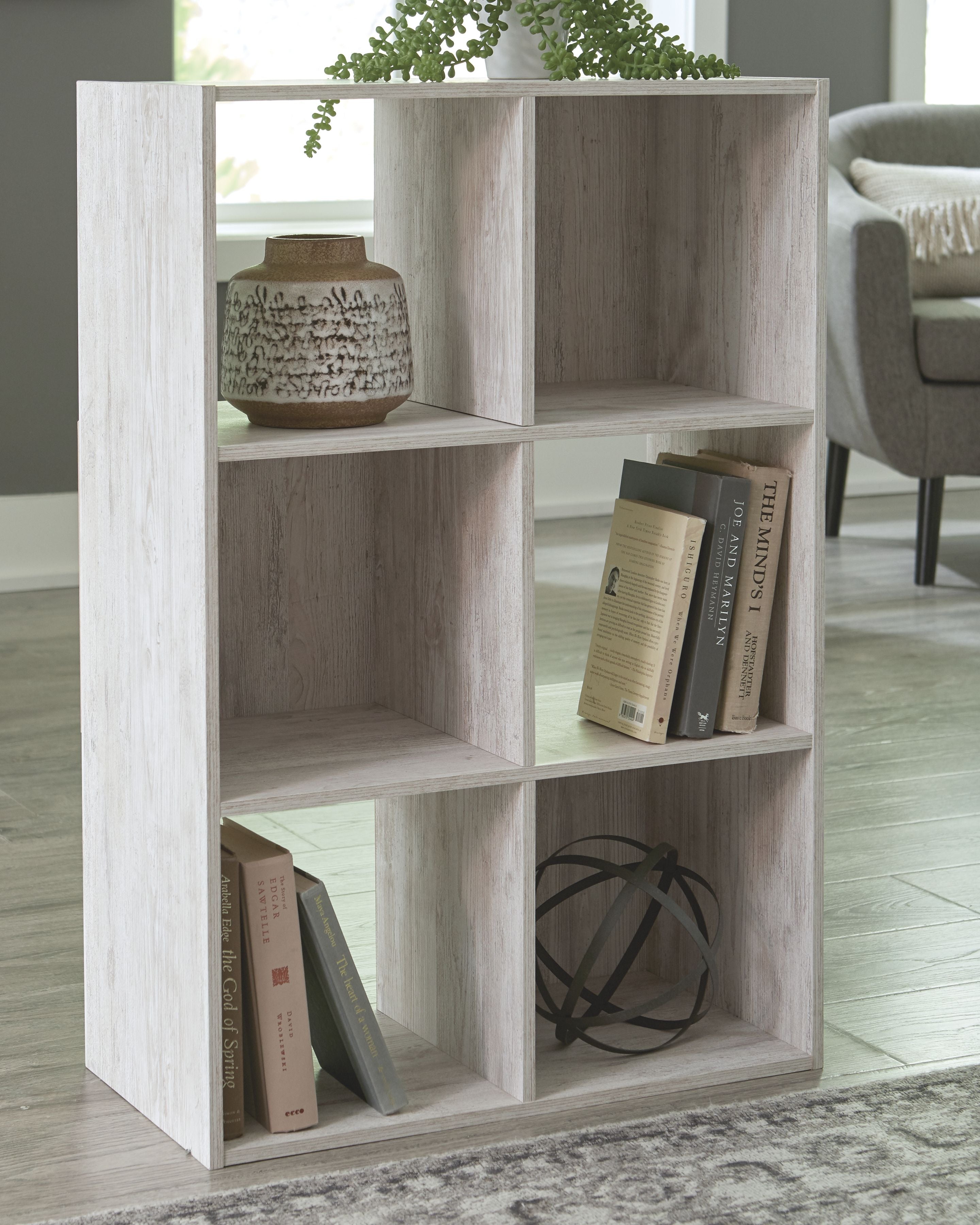 Whitewashed wood cube organizer with open cubbies holding books and decor