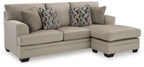 Corner sectional sofa with chaise, light gray upholstery and multiple patterned throw pillows