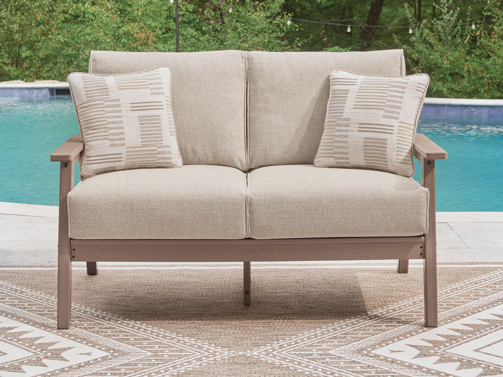 Outdoor loveseat with driftwood arms, light gray seat cushion, and two patterned pillows.
