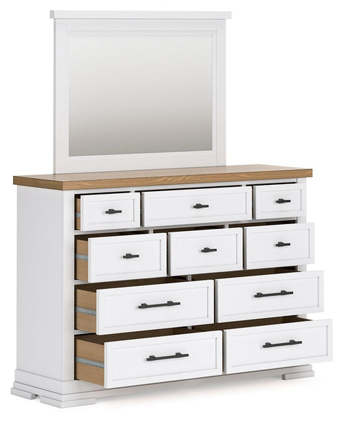White dresser with mirror, light wood top, multiple drawers with black bar pulls