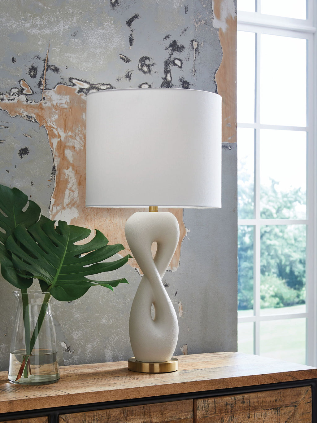 White fabric table lampshade on sculpted poly lamp base with gold-finish feet