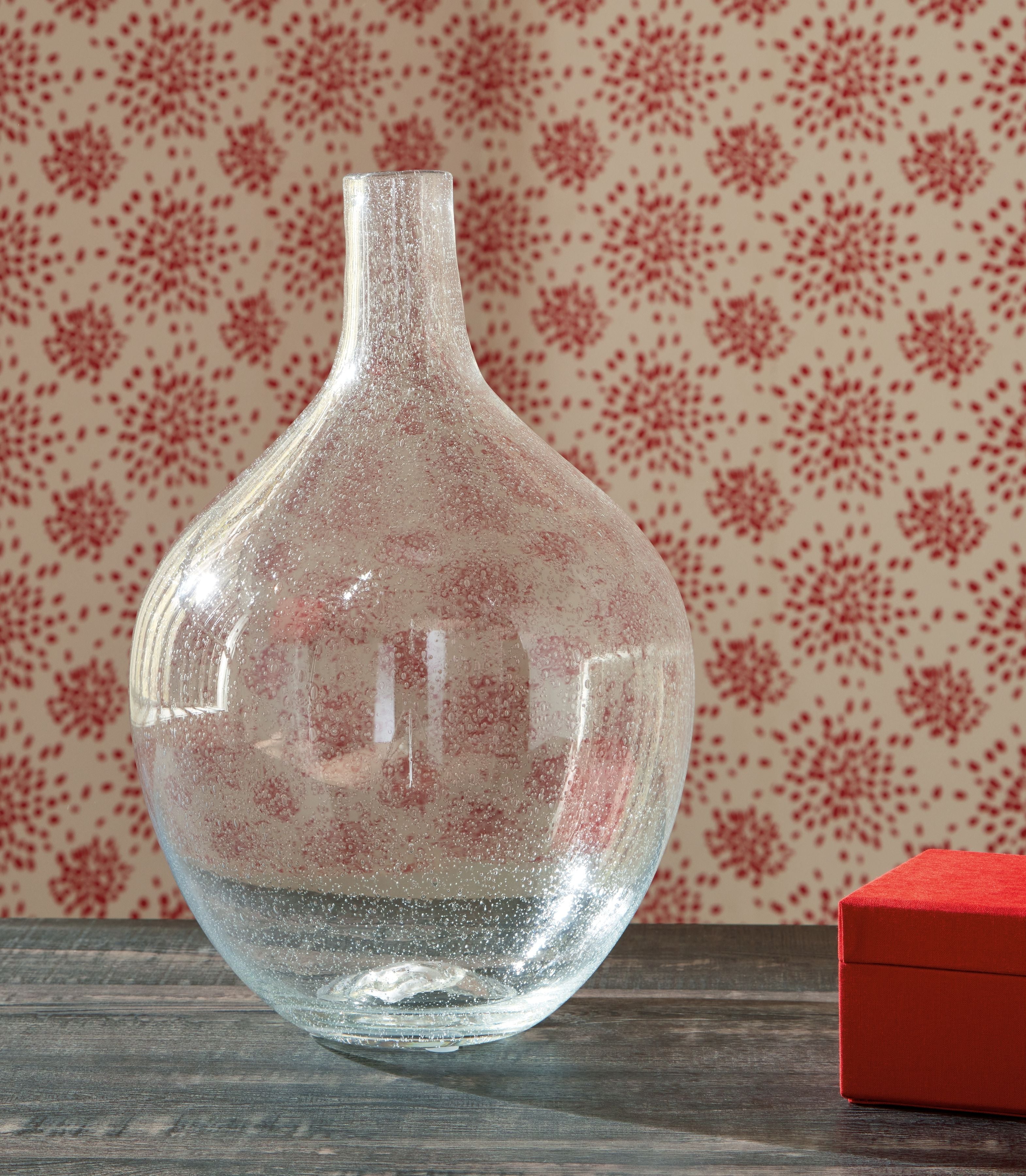 Speckled clear glass vase with narrow neck and rounded body, glossy surface.