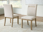Light beige upholstered dining side chair, angled view, gold bar across the back