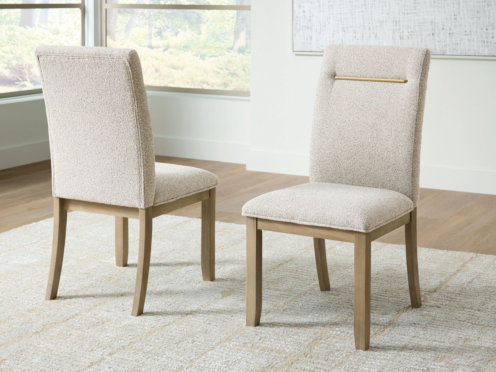 Light beige upholstered dining side chair, angled view, gold bar across the back