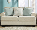 Upholstered sofa with light beige base and three blue accent pillows