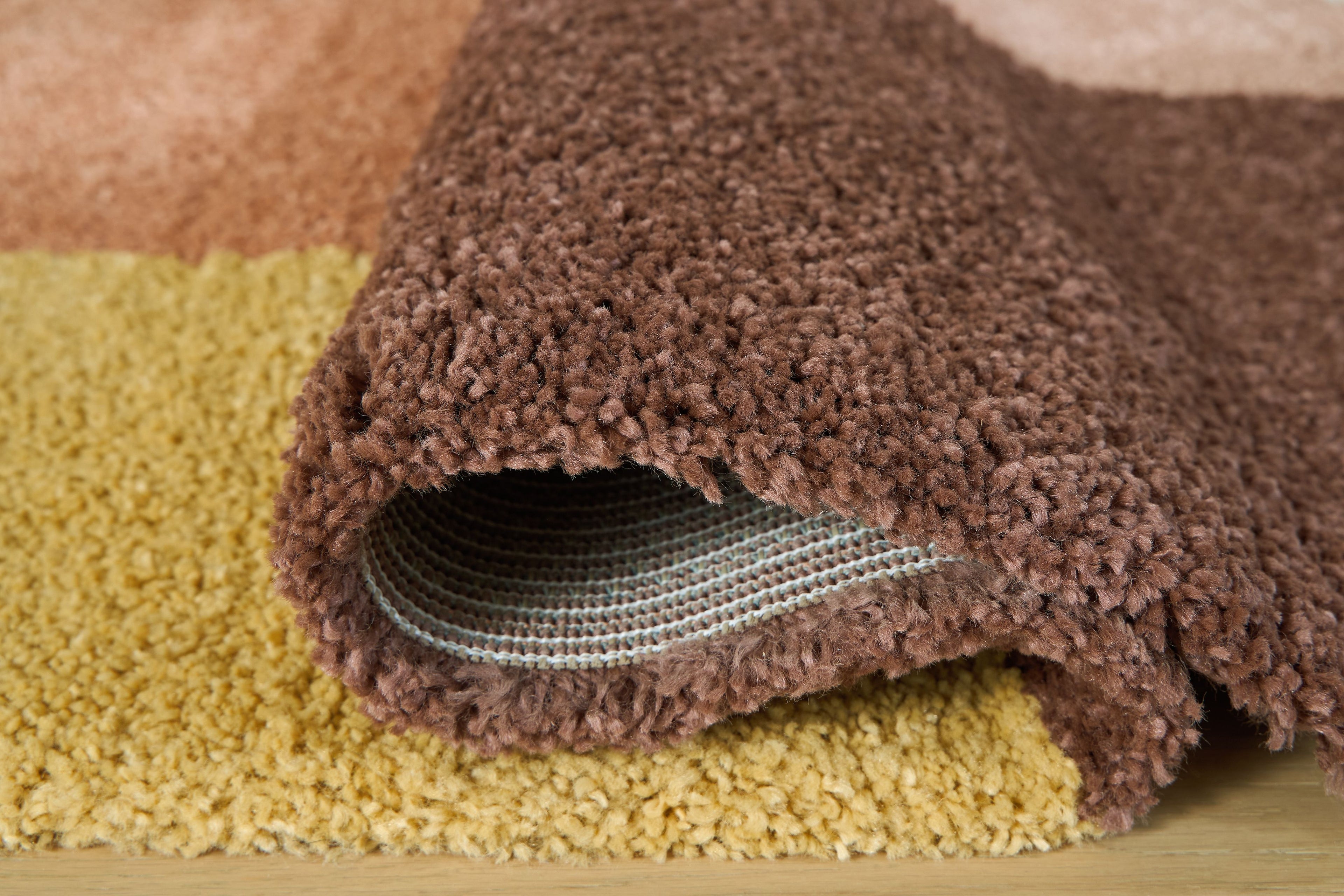 Geometric area rug corner with textured shag pile and visible gray backing