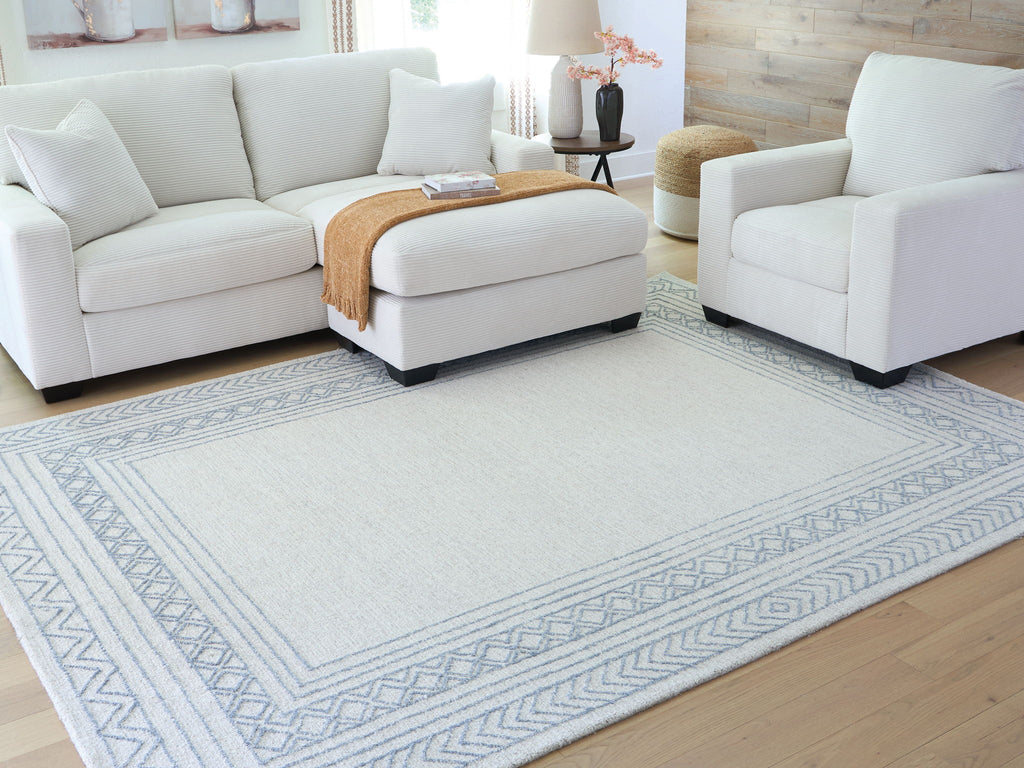 Geometric blue rug with wide border pattern, shown under seating