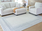 Geometric blue rug with wide border pattern, shown under seating