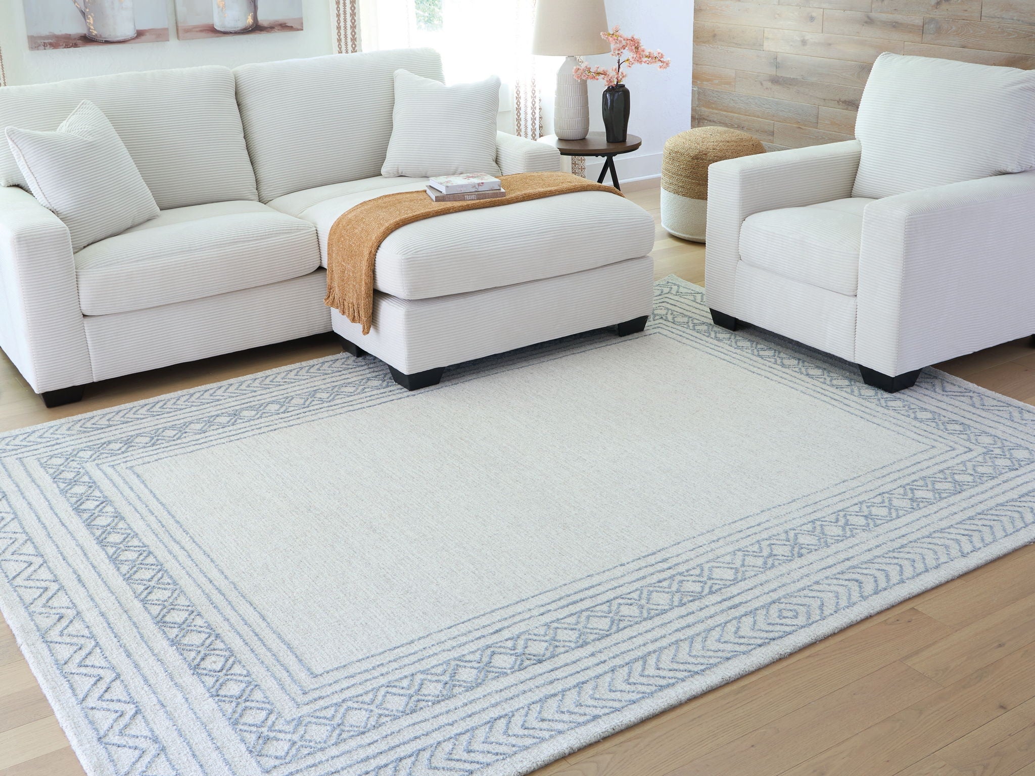 Geometric blue rug with wide border pattern, shown under seating