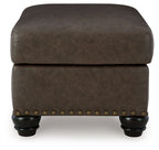 Dark brown tuftless ottoman with nailhead band and short turned legs