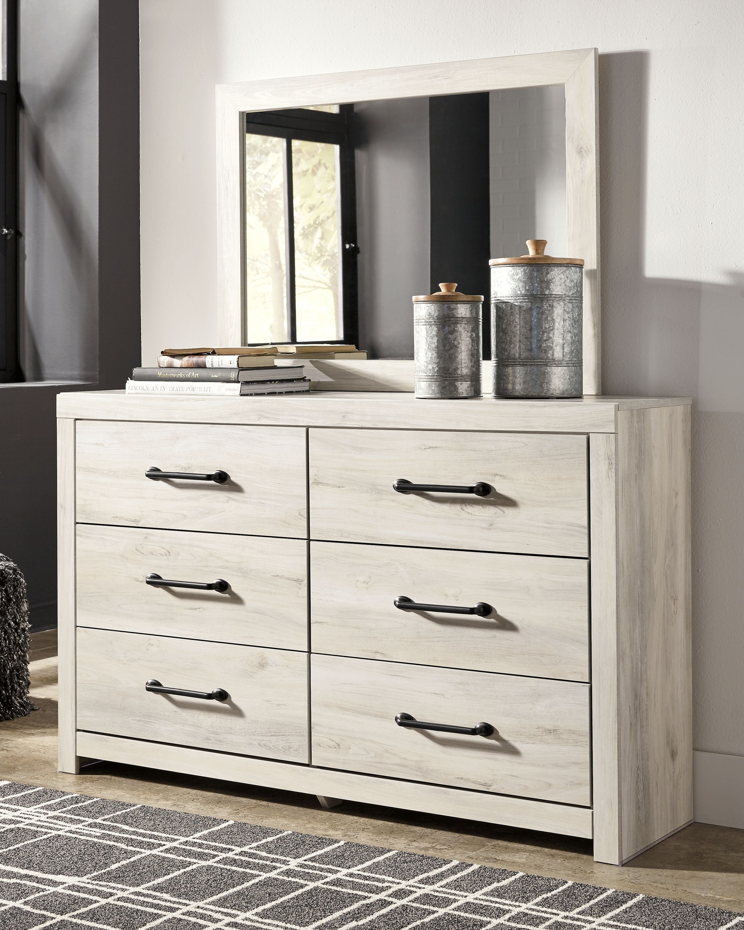 Light wood cabinet dresser with six drawers and black bar pulls, shown with decor