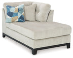 Stone corner chaise with sloped arms, tufted back cushions, and dark legs