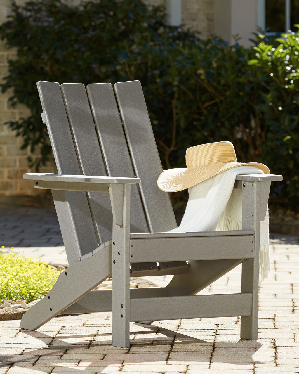 Gray Adirondack chair with slatted back and arms, outdoor patio view