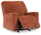 Rocker recliner chair in rust-orange upholstered fabric with extended footrest and padded arms.