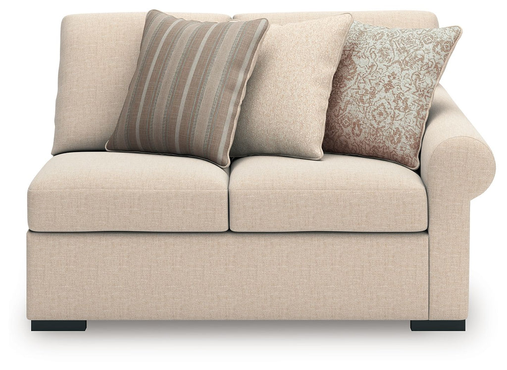 Light beige loveseat with three back cushions and striped and patterned accent pillows