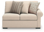 Light beige loveseat with three back cushions and striped and patterned accent pillows