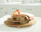 Kaidler brown wooden tray set with three stacked rounds, topped with fruit and napkin