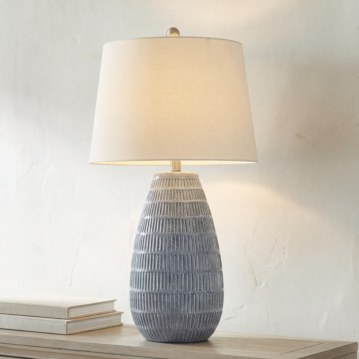 Ceramic table lamp with white drum shade and tall blue-gray textured ceramic base