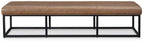 Low caramel brown bench with padded top and black steel base, side view