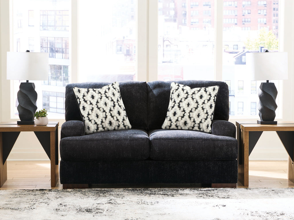 Dark charcoal loveseat with two black-and-white patterned pillows on the backrest