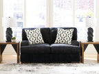 Dark charcoal loveseat with two black-and-white patterned pillows on the backrest