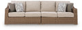 Beige loveseat with seat cushions and two patterned throw pillows, woven base.