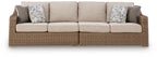 Beige loveseat with seat cushions and two patterned throw pillows, woven base.
