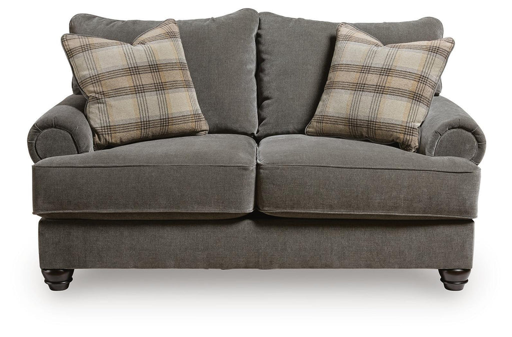Gray loveseat with rounded arms, two seat cushions, and plaid throw pillows