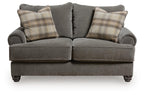 Gray loveseat with rounded arms, two seat cushions, and plaid throw pillows