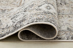 Geometric rug corner with stitched edge and gray patterned pile, off-white underside
