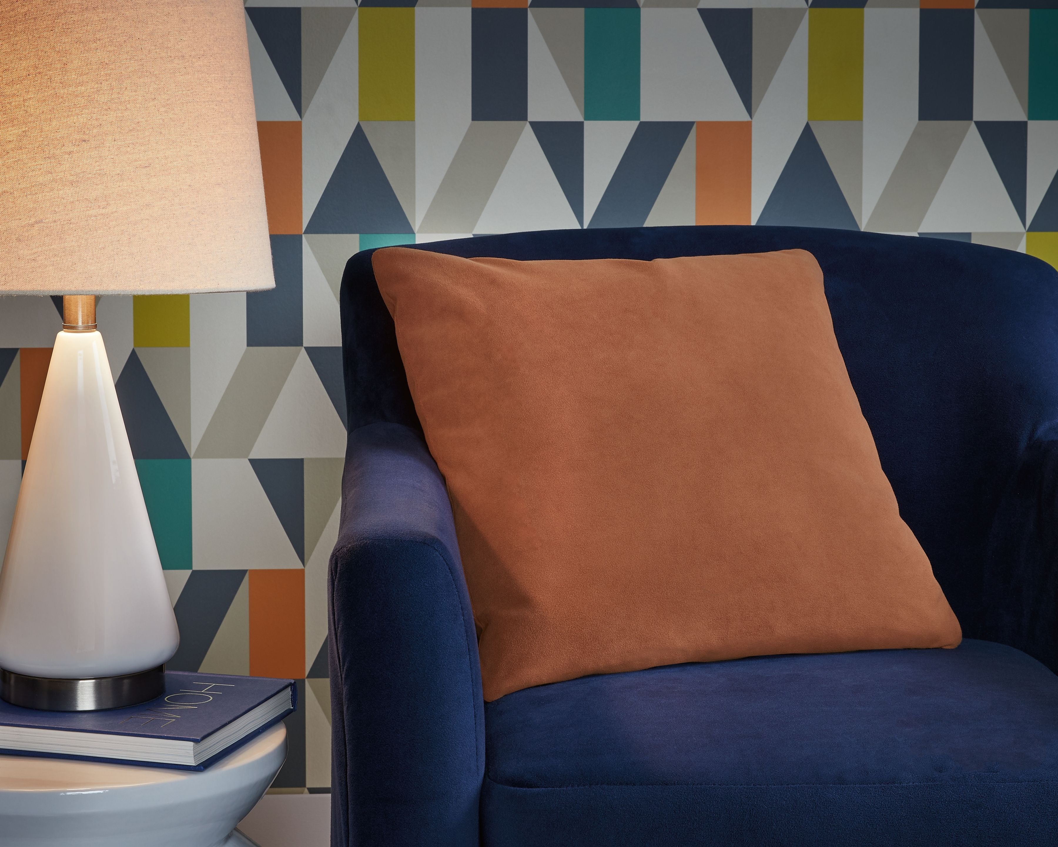Light brown throw pillow on a dark blue sofa, textured surface