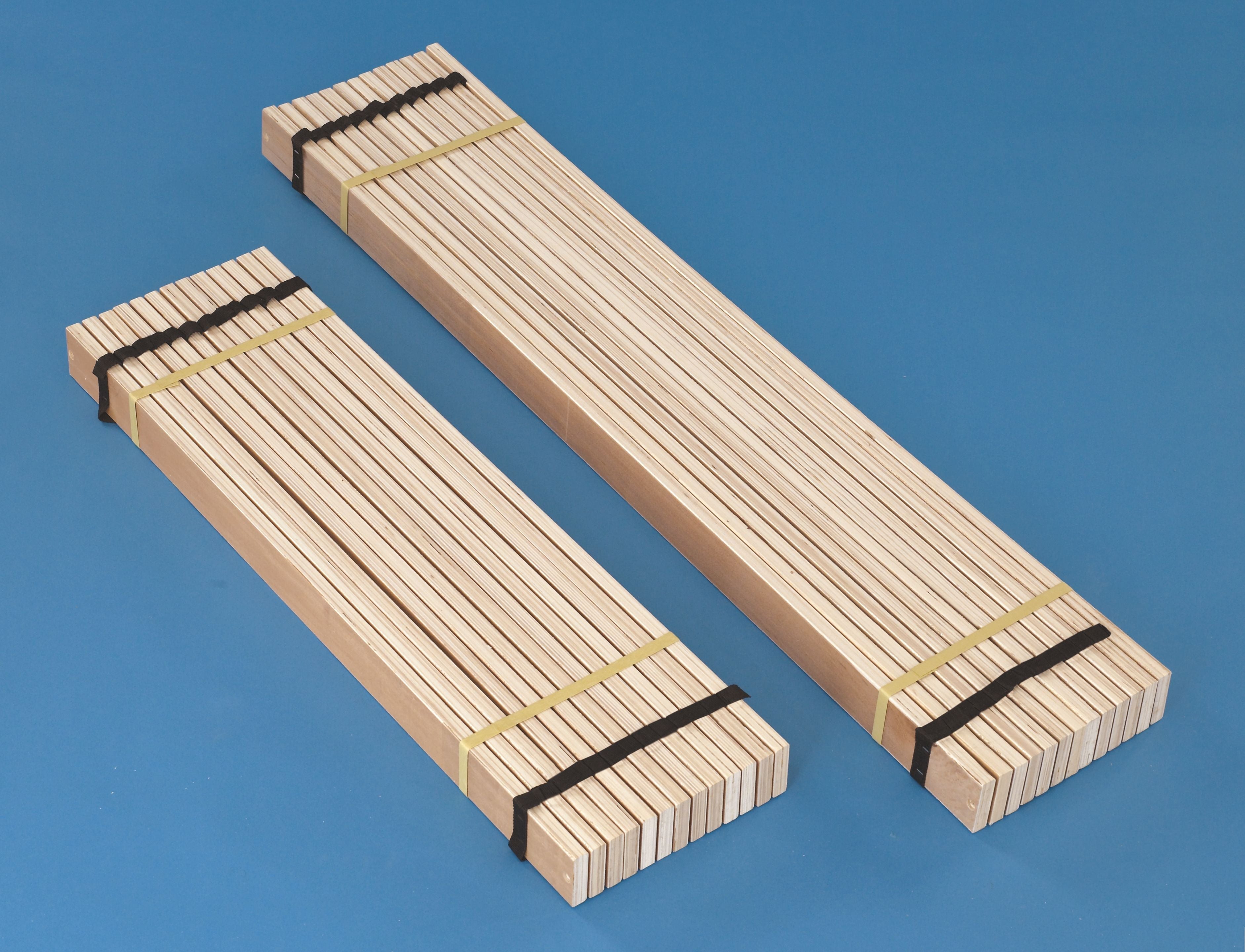 Brown wooden twin roll slats, two rolled bundles tied with black straps