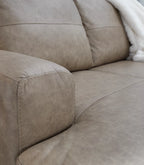 Beige sectional sofa arm and chaise seat cushions with visible stitching
