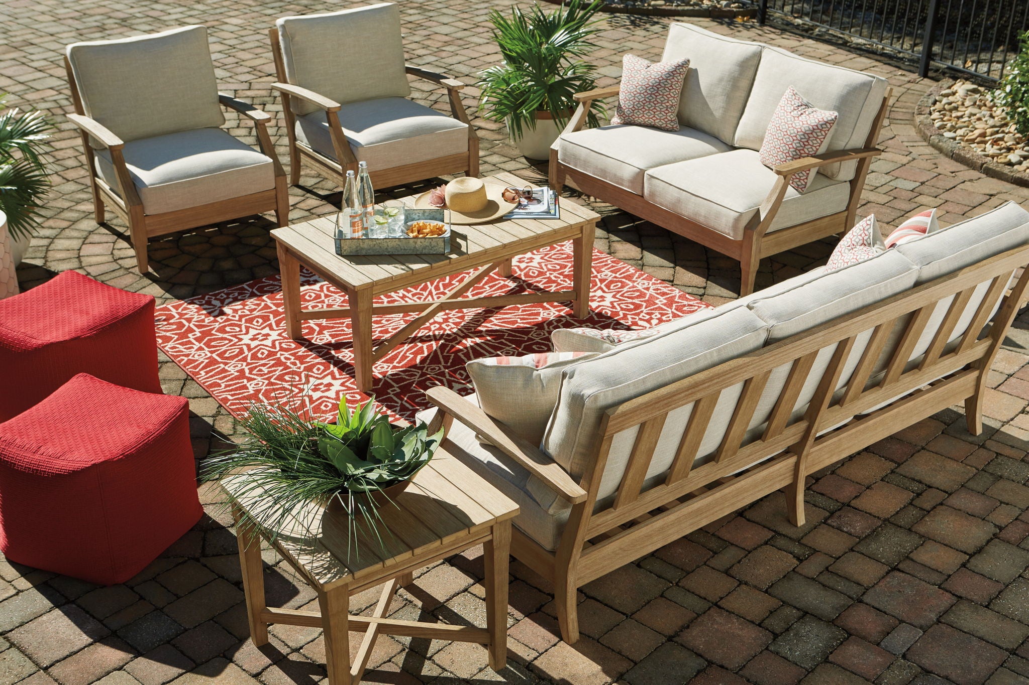 Beige outdoor lounge set with sofa seating, chairs, and patterned pillows