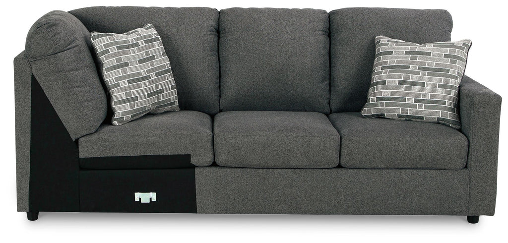 Dark gray wedge sofa with two patterned pillows and a light side panel