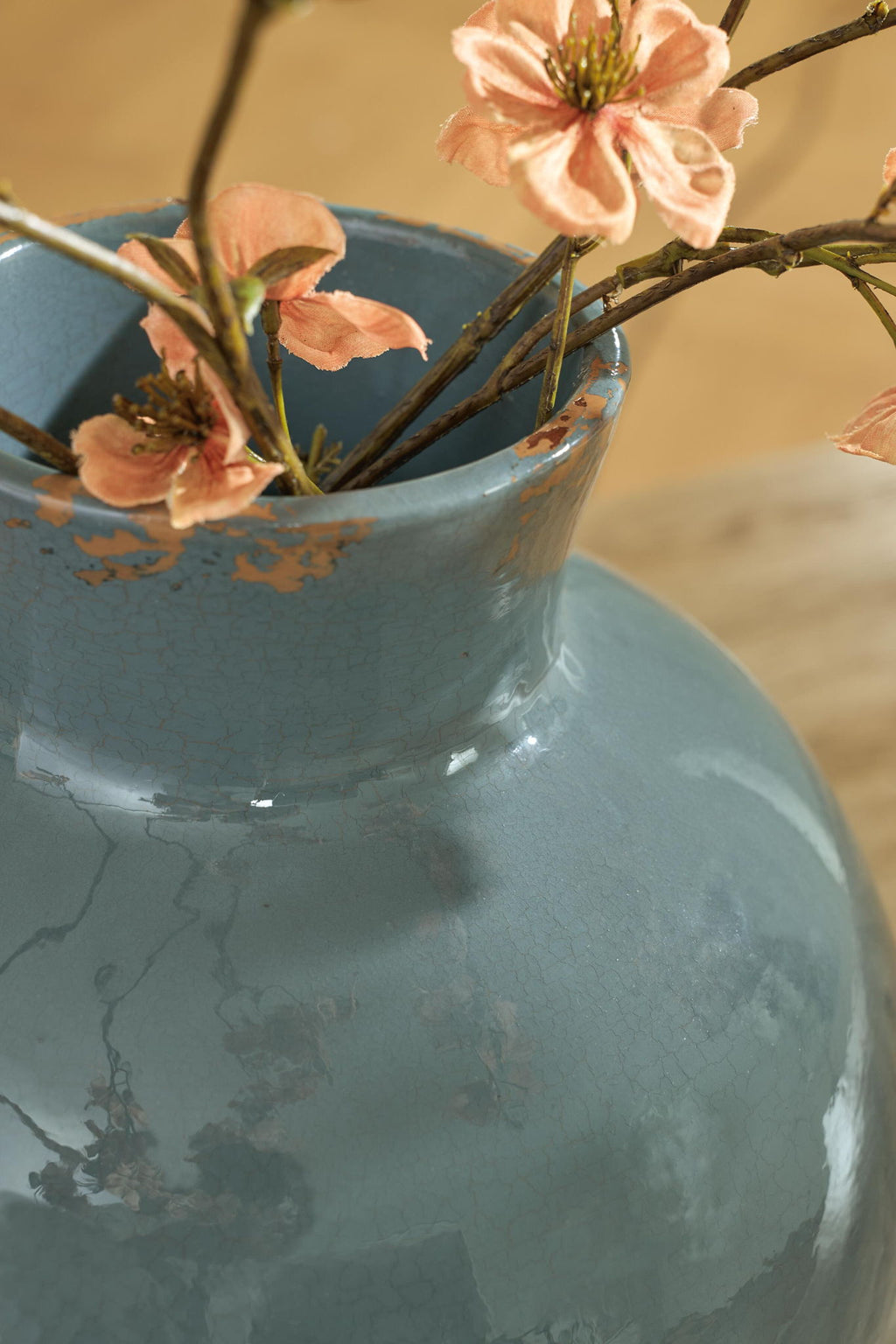 Blue ceramic vase neck with orange speckled glaze and small peach flower stems
