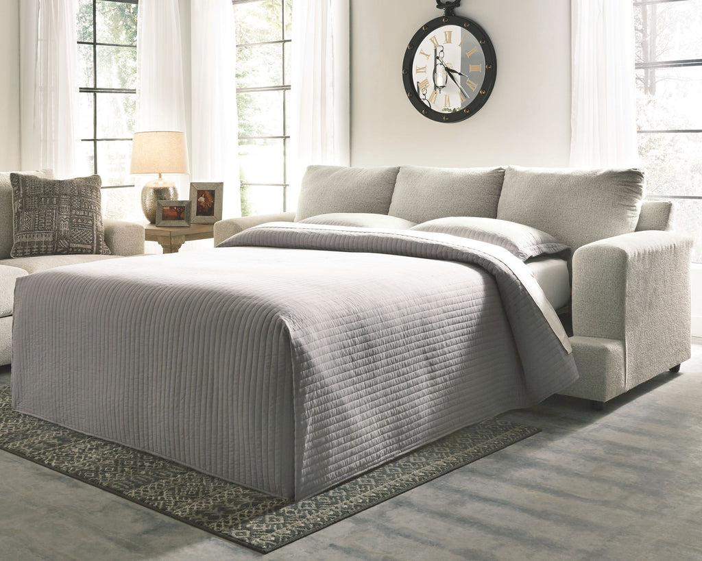 Stone sleeper sofa converted to bed with gray striped bedding and pillows