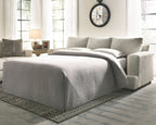 Stone sleeper sofa converted to bed with gray striped bedding and pillows