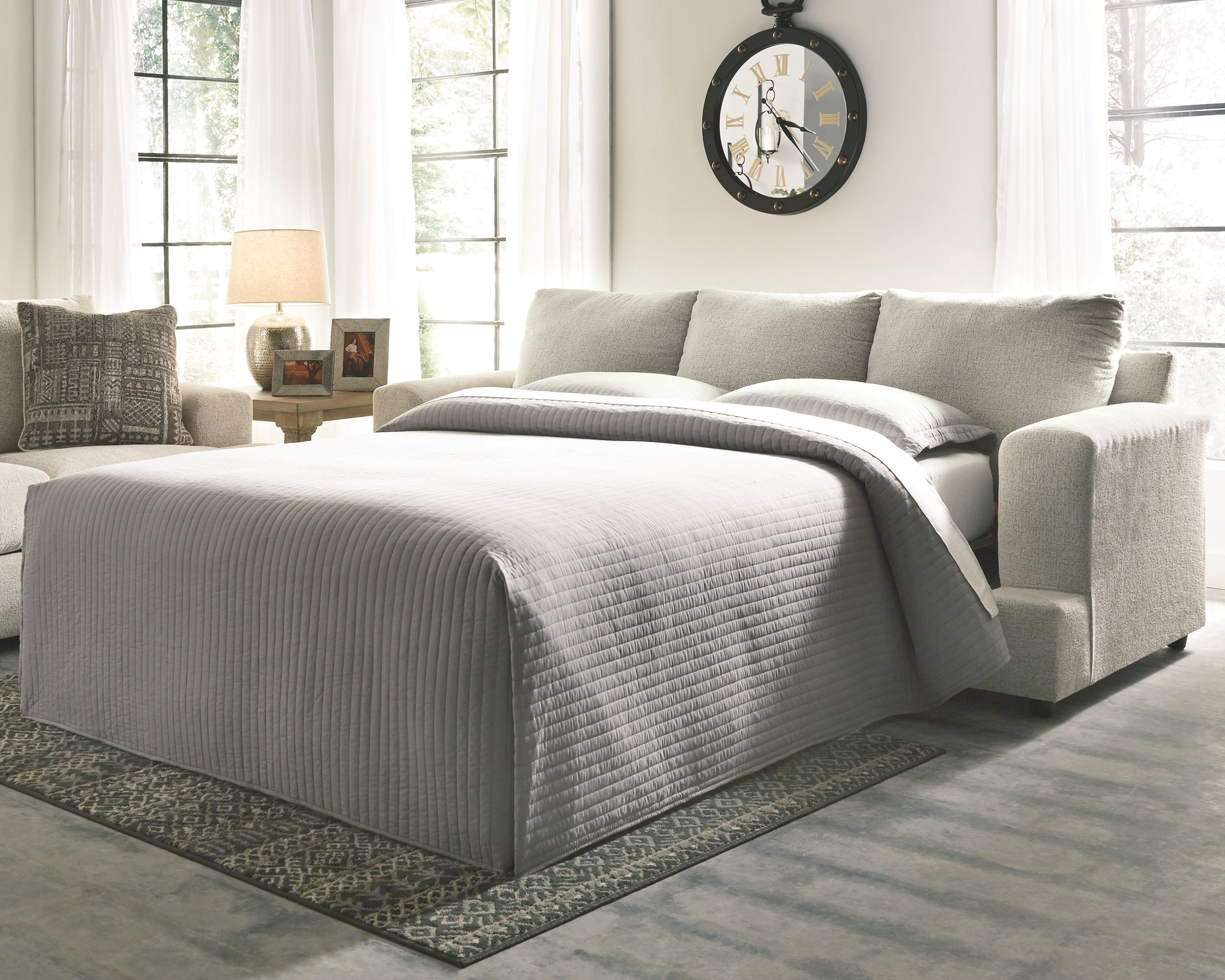 Stone sleeper sofa converted to bed with gray striped bedding and pillows