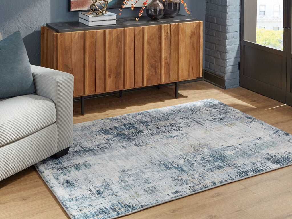 Blue and white abstract area rug with faded pattern, in a living room setting