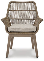 Beige wicker armchair with gray cushion, curved arms and woven slatted back