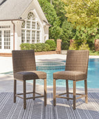 Woven bar stools with tall backrest, curved seat, light wood legs, and footrest