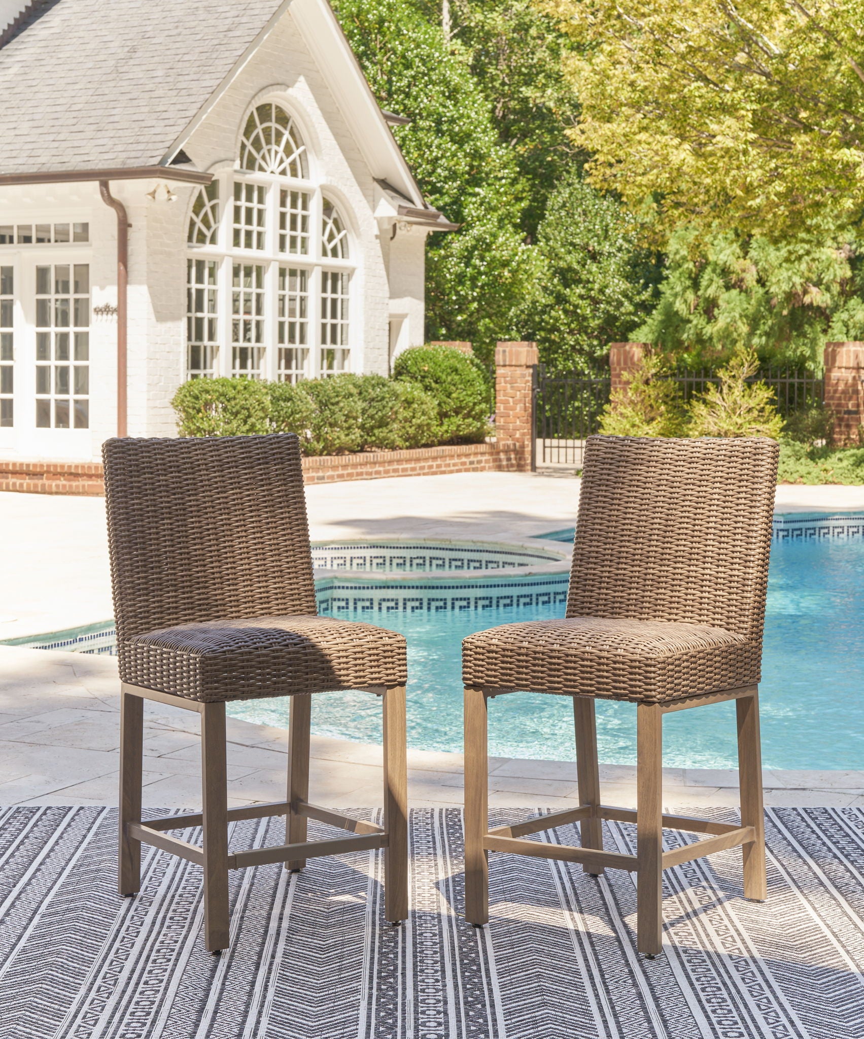 Woven bar stools with tall backrest, curved seat, light wood legs, and footrest